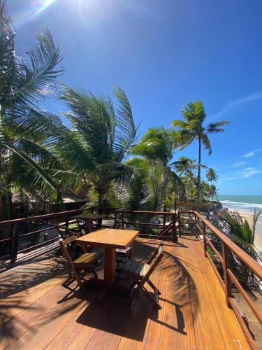 a wooden deck with a table and chairs on the beach at Pontal dos Sonhos- Chalés Praia do Farol in Coruripe