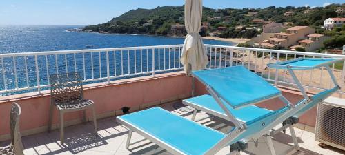 a blue chair and a chair on a balcony with the ocean at Résidence Villa Nova in Tiuccia
