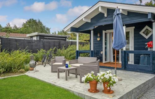 a blue house with a patio with chairs and an umbrella at Awesome Home In Kalundborg With Wifi in Kalundborg