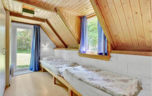 two beds in a room with wooden ceilings and windows at Holiday Home Vester Mosevej Ulfborg Iv in Øhuse