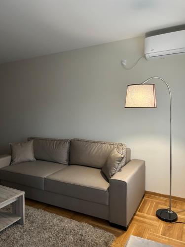 a living room with a couch and a lamp at Apartmani CENTAR Vrnjacka Banja & Free Parking in Vrnjačka Banja