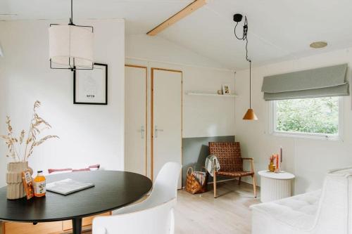 una sala da pranzo con tavolo nero e sedie bianche di Boshuisje Lou op de Veluwe a Hattemerbroek