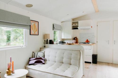 un soggiorno con un divano bianco e una cucina di Boshuisje Lou op de Veluwe a Hattemerbroek