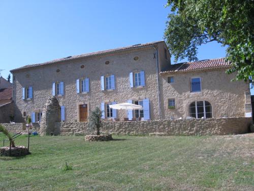 a large stone building with an umbrella in front of it at Mas Du Puits in Courthézon