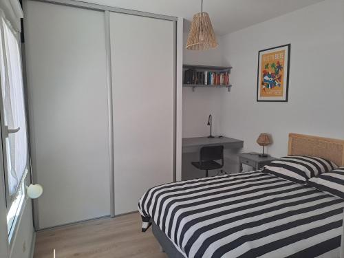 - une chambre avec un lit rayé noir et blanc et un bureau dans l'établissement L'Oustal de Provence, à Sète