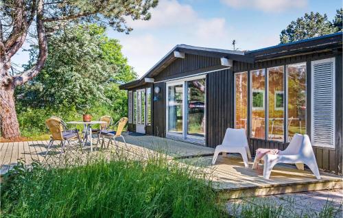 ein winziges Haus mit einem Tisch und Stühlen auf einer Terrasse in der Unterkunft Three-Bedroom Holiday Home In Martofte in Martofte