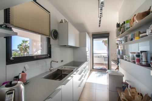 une cuisine avec des armoires blanches, un évier et une fenêtre dans l'établissement Le Murano Sea Sete and Art, à Sète