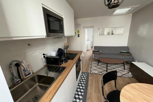 une cuisine avec un évier et un canapé dans une chambre dans l'établissement Flexliving - room - Caulaincourt, à Paris