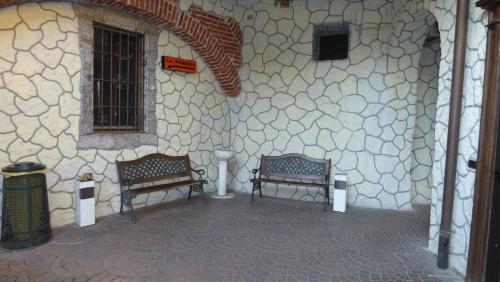 two benches sitting in front of a stone wall at La Pergola in Zibido San Giacomo