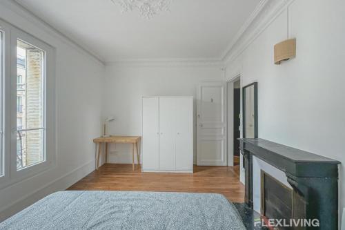 Cette chambre blanche dispose d'une cheminée et d'un lit. dans l'établissement Flexliving - Room - Henri Sellier - Suresnes 92, à Suresnes