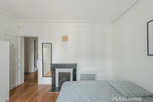 Cette chambre blanche dispose d'un lit et d'une cheminée. dans l'établissement Flexliving - Room - Henri Sellier - Suresnes 92, à Suresnes