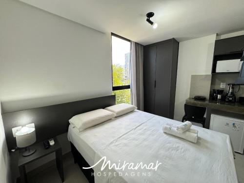 een slaapkamer met een bed met witte lakens en een raam bij Ozean Home Service - Jardim Oceania in Tambaú