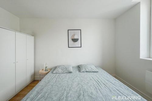 - une chambre blanche avec un lit et une couverture bleue dans l'établissement Flexliving - Room - Henri Sellier - Suresnes 92, à Suresnes