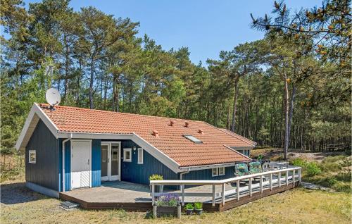 une petite maison bleue avec une terrasse couverte dans les bois dans l'établissement Holiday Home Mejsevej Nexø Ii, à Spidsegård