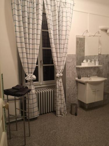 La salle de bains est pourvue d'un lavabo et d'une fenêtre avec des rideaux. dans l'établissement Château de Saint-Georges Chambres d Hôtes, à Athesans