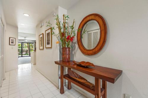 a hallway with a table with a mirror and flowers at Tropical Paradise 1-bed 2-bath Oasis At The Pool in Wailea