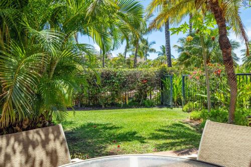 a yard with palm trees and a table and chairs at Tropical Paradise 1-bed 2-bath Oasis At The Pool in Wailea