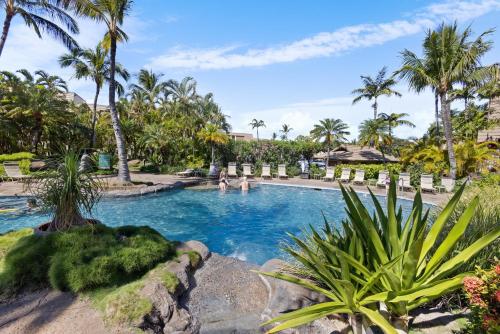 a swimming pool with palm trees and people in it at Tropical Paradise 1-bed 2-bath Oasis At The Pool in Wailea