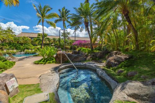 a pool with a waterfall in a backyard with palm trees at Tropical Paradise 1-bed 2-bath Oasis At The Pool in Wailea