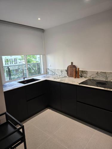 une cuisine avec comptoirs en noir et blanc et une fenêtre dans l'établissement Henri martin, vue Tour Eiffel Trocadéro luxe et chic, à Paris