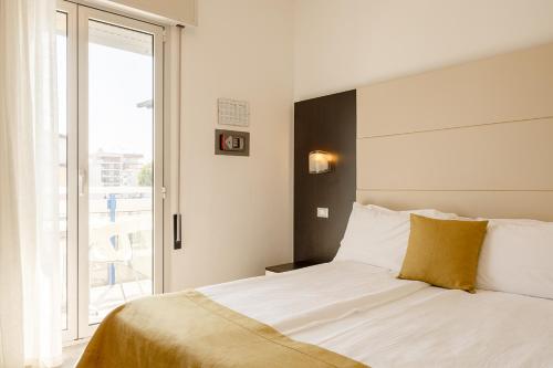 a bedroom with a white bed with a large window at Hotel Bristol in Caorle