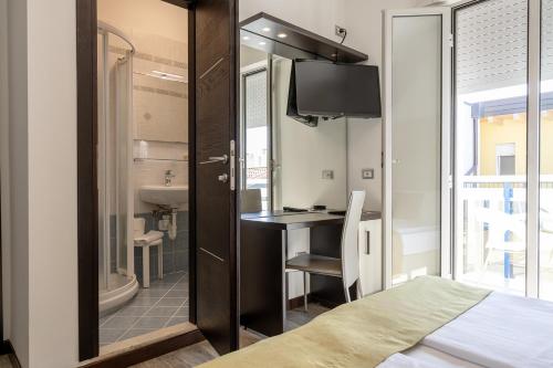 a bedroom with a bed and a desk and a bathroom at Hotel Bristol in Caorle