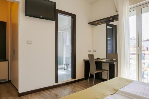 a bedroom with a bed and a desk with a television at Hotel Bristol in Caorle