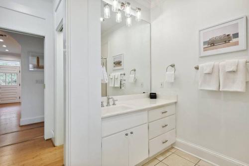 a white bathroom with a sink and a mirror at Charming Cottage and Guest House a block to beach! in Gulfport