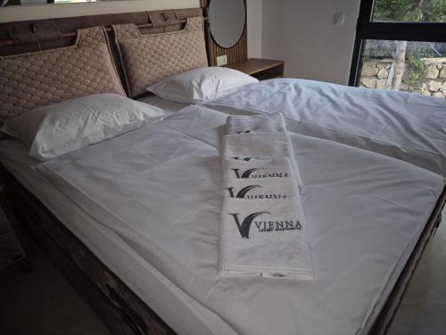 a bed with white sheets and two towels on it at Vienna Luxury Apartments in Dobra Voda