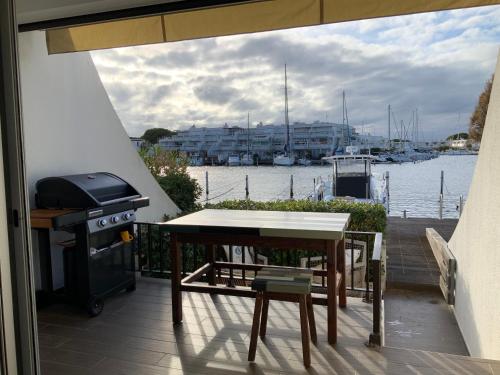un grill et une table sur un balcon avec vue sur l'eau dans l'établissement marina avec son bateau, au Grau-du-Roi