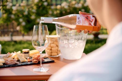 a person pouring a bottle of wine into a glass at Le Bignele in Marano di Valpolicella