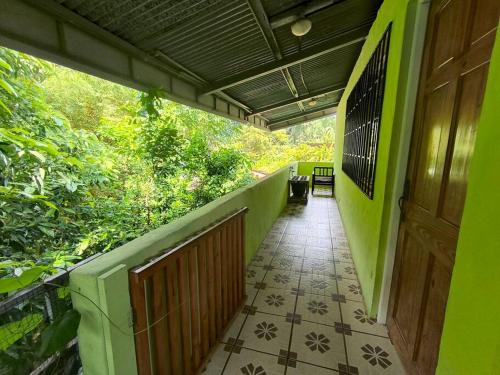 Una pasarela en un edificio verde con una puerta de madera. en Downtown, en Quepos
