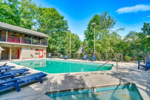 a swimming pool with two blue chairs and a house at Smoky Mountain Cabin with Deck and Hot Tub! in Pigeon Forge