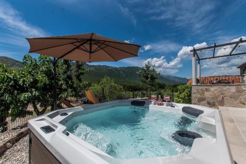 a hot tub with an umbrella on a patio at Villa Le Adria - Privat HotTub - Kostenloser Strandparkplatz in Kozica