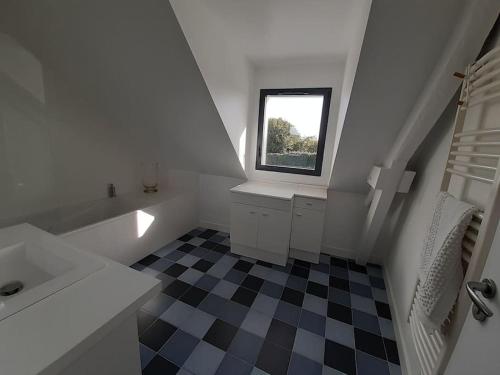 - une salle de bains blanche avec un sol en damier noir et blanc dans l'établissement Charmante maison golfe du Morbihan, à Saint-Armel