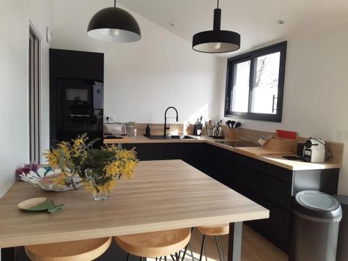 une cuisine avec une table en bois et des fleurs. dans l'établissement Charmante maison golfe du Morbihan, à Saint-Armel