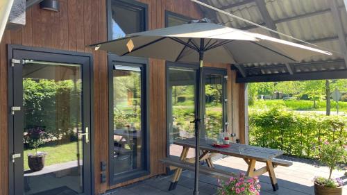 an umbrella over a picnic table on a patio at JouwvakantiehuisNL 8 persoons cottage in Vries