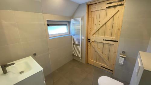 a bathroom with a toilet and a wooden door at JouwvakantiehuisNL 8 persoons cottage in Vries