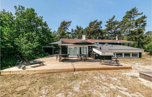 a house with a deck with chairs and an umbrella at Amazing Home In Nexø With Sauna in Snogebæk