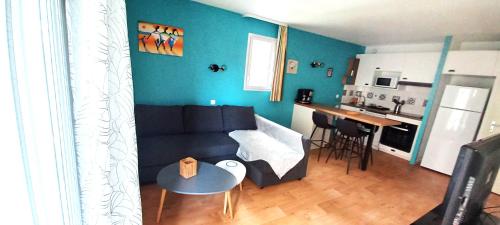 een woonkamer met een bank en een tafel en een keuken bij Entre Golf et Mer in Pornic