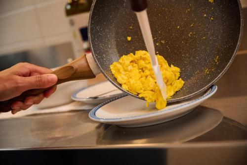 a person is stirring eggs in a wok at Le Bignele in Marano di Valpolicella