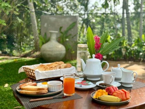 a table with a tray of bread and orange juice at TRES Galle in Galle