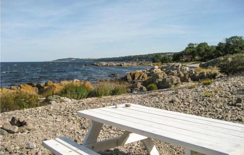 a white bench sitting on the rocks near the water at Awesome Home In Gudhjem With Wifi in Gudhjem
