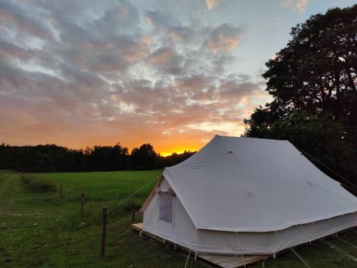 a white tent in a field at sunset at Under Canvas Bornholm in Østermarie