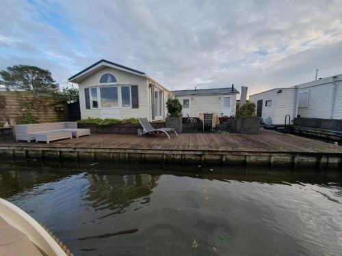 a house on a dock next to a body of water at Chalet op Zee in Wervershoof mit Seeblick und Terrasse mit eigenen Zugang zum Wasser in Wervershoof