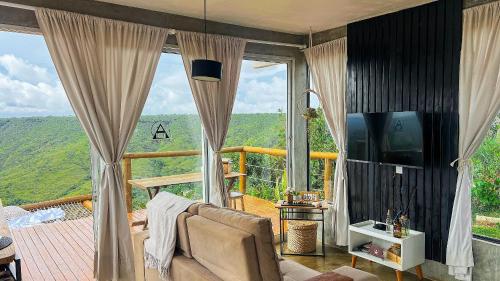 a living room with a couch and a large window at Cabana Valley - Hóspedagem Romântica in Papuda
