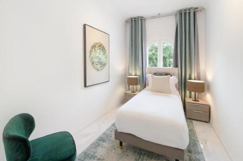 - une chambre avec un lit et une chaise verte dans l'établissement Palais Alexandre, à Cannes