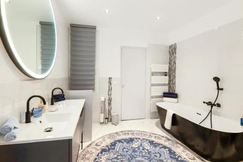une salle de bain avec une baignoire, un lavabo et un miroir dans l'établissement Palais Alexandre, à Cannes