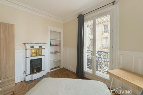- une chambre avec une cheminée et une grande fenêtre dans l'établissement Flexliving - Room - Lamarck, à Paris