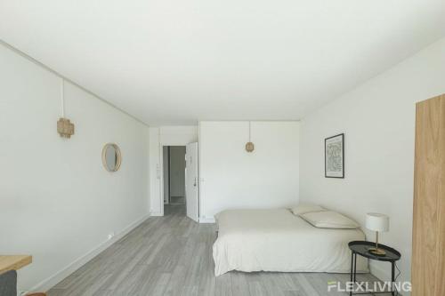 une chambre blanche avec un lit et une table dans l'établissement Flexliving - room - Mouchez, à Paris